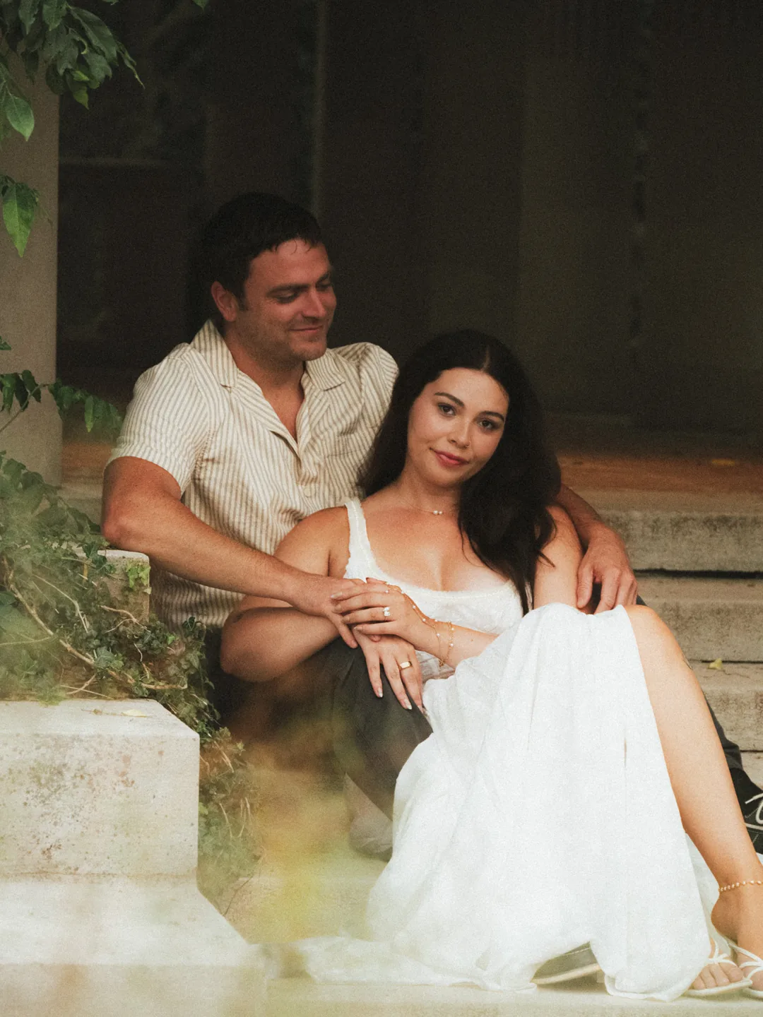 A couple sitting close together on stone steps in warm light.